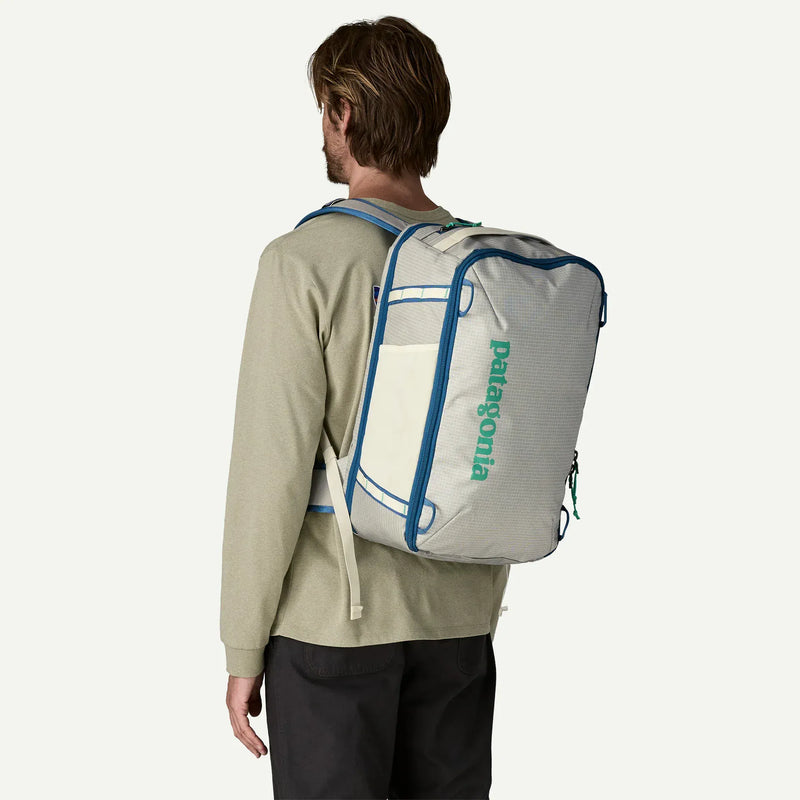 Load image into Gallery viewer, Person wearing a white Patagonia backpack with blue trim on a plain background