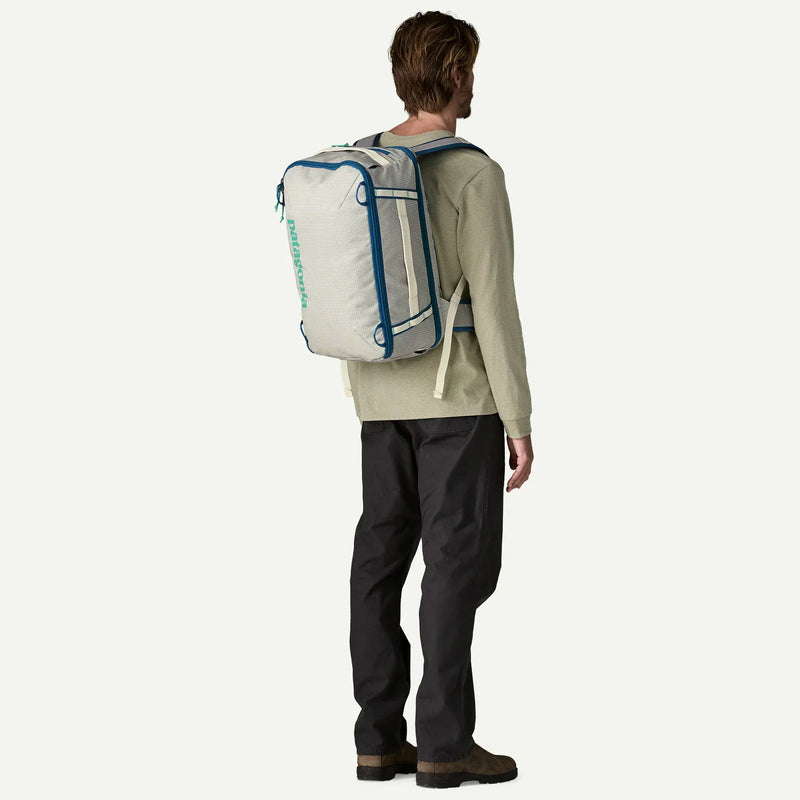 Load image into Gallery viewer, Person wearing a large white patagonia backpack with blue accents on a white background