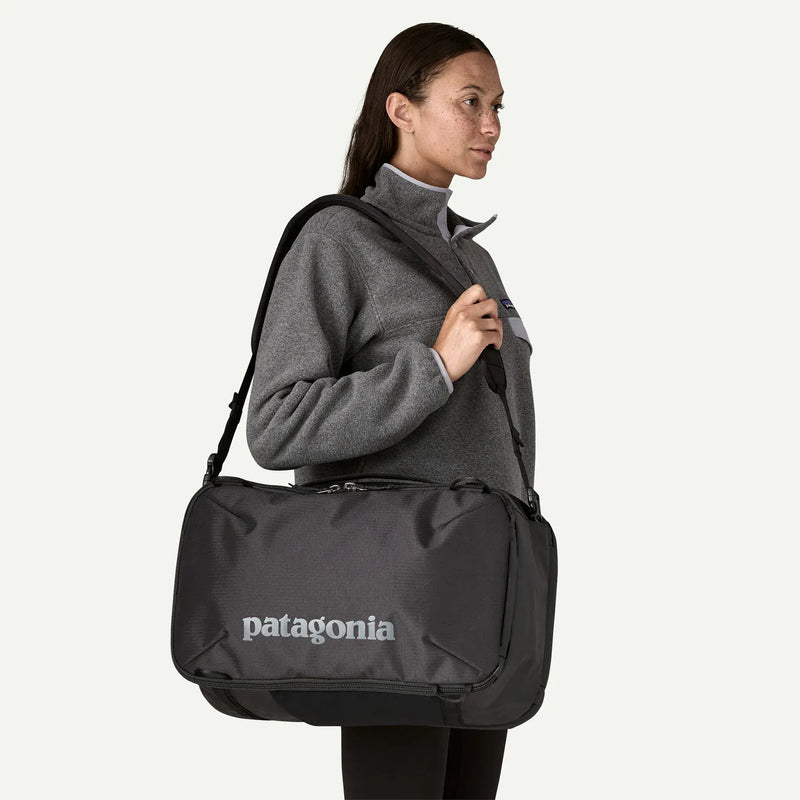 Load image into Gallery viewer, Person carrying a black Patagonia bag on a white background