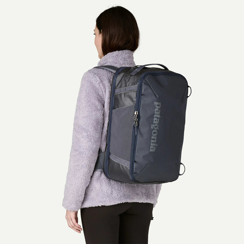 Load image into Gallery viewer, Person wearing a navy and grey Patagonia backpack on a white background