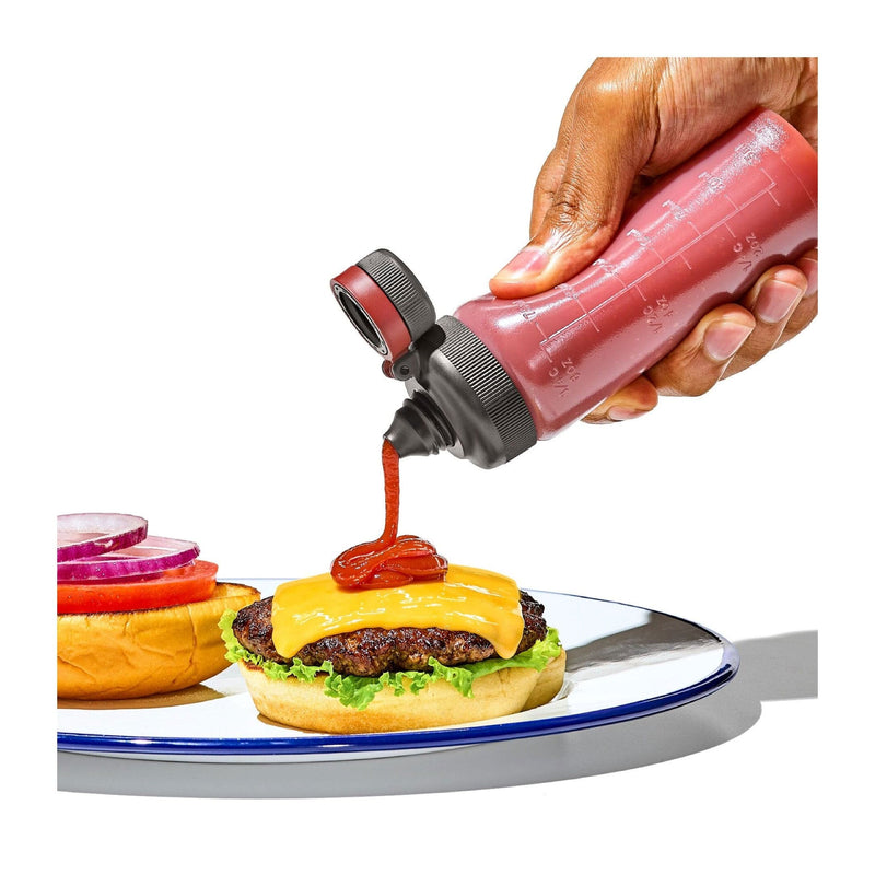 Load image into Gallery viewer, Hand pouring ketchup from a bottle onto a hamburger on a white background