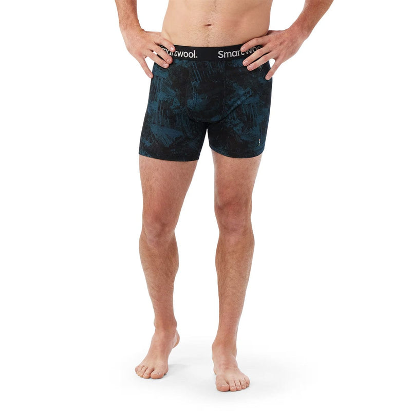 Load image into Gallery viewer, Person wearing black patterned boxer briefs with 'Smartwool' branding on a white background