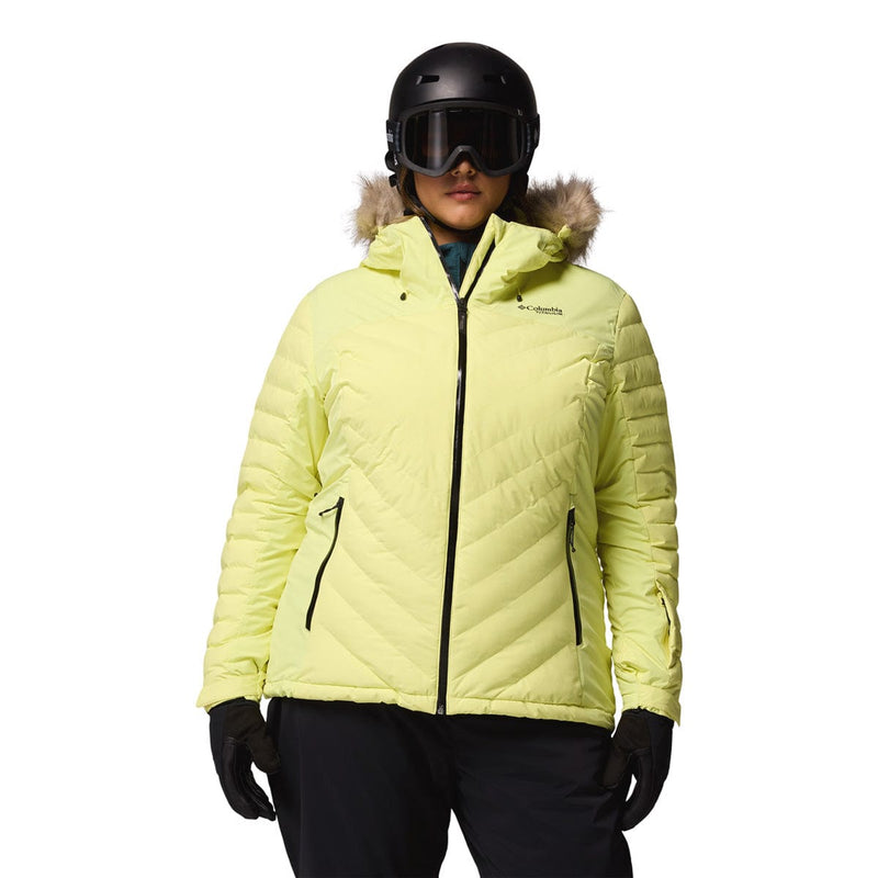 Load image into Gallery viewer, Person wearing a bright yellow winter jacket with a brand logo, black helmet, and goggles on a white background.