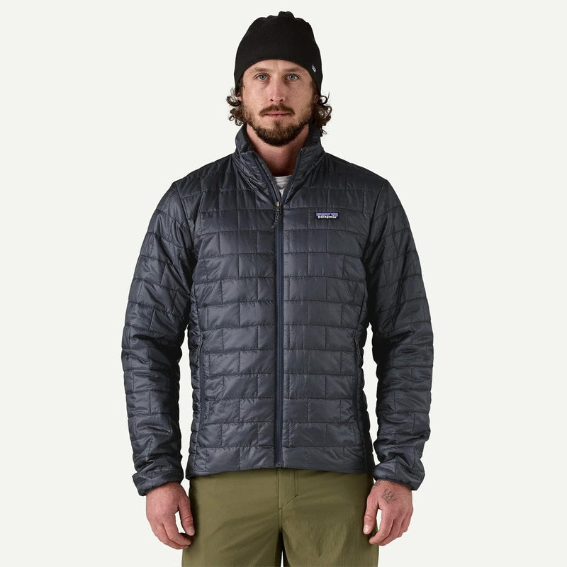 Load image into Gallery viewer, Man wearing a dark gray quilted jacket with a brand logo on a white background