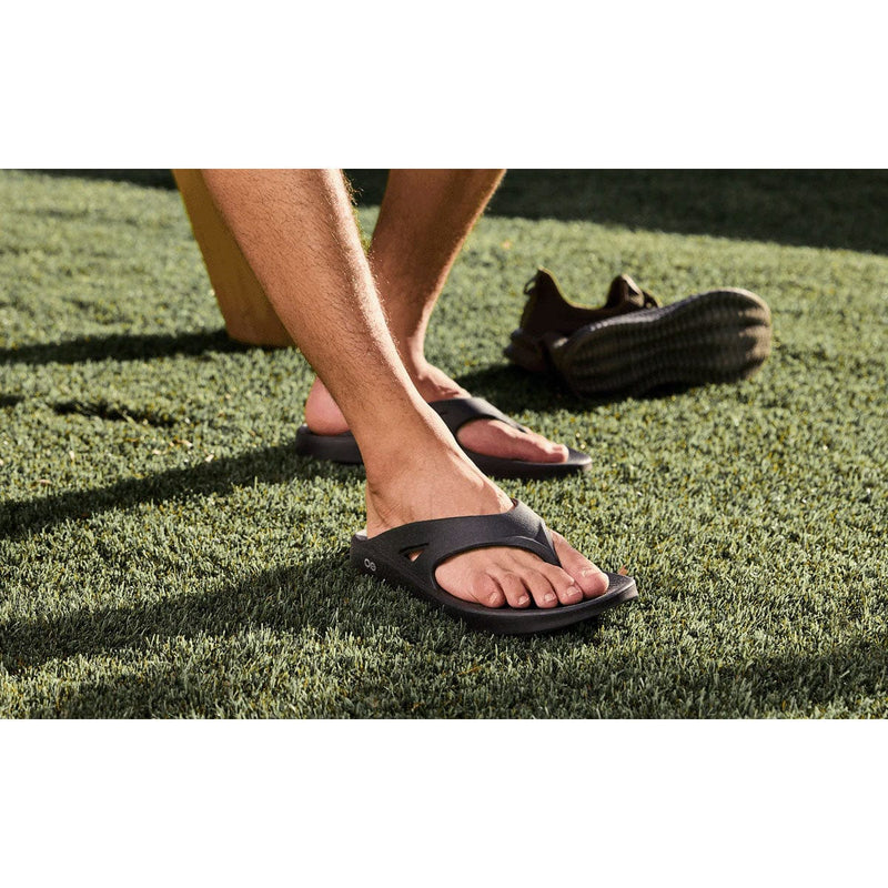 Load image into Gallery viewer, Person wearing black sandals on grass
