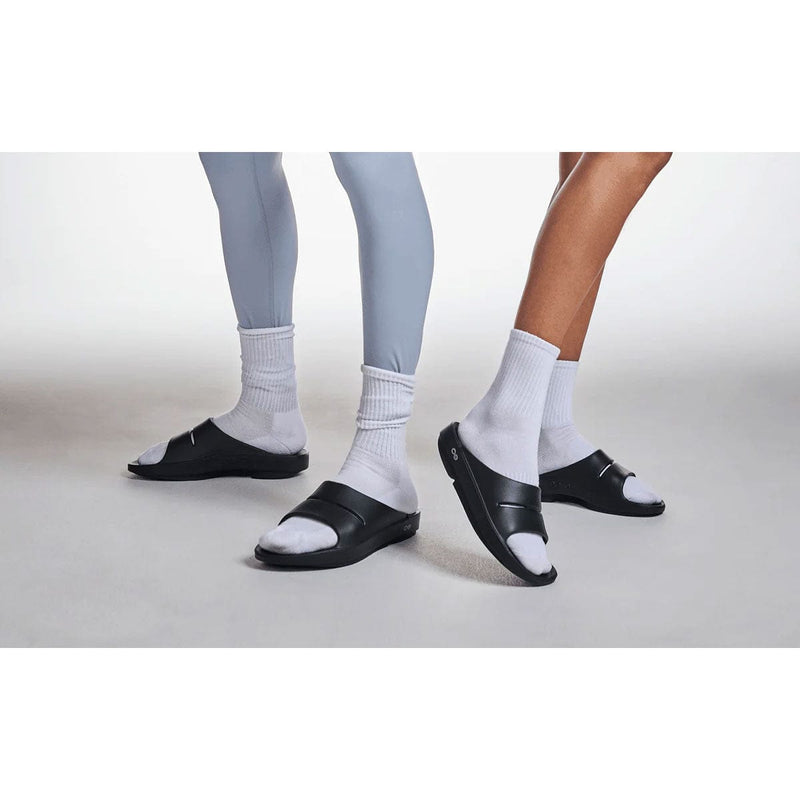 Load image into Gallery viewer, Two pairs of feet wearing black sandals and white socks on a light gray background
