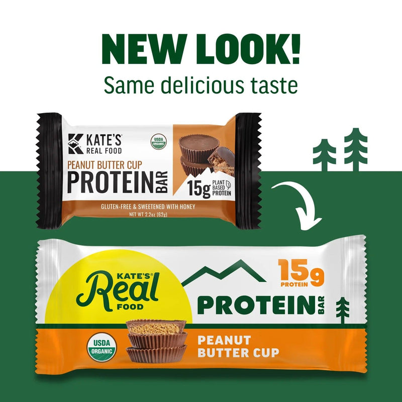 Load image into Gallery viewer, Two versions of Kate's Real Food peanut butter cup protein bar packaging with a green background and trees.
