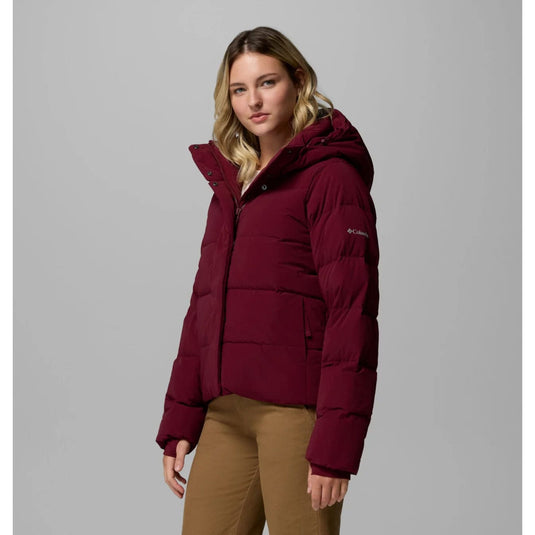 Woman wearing a maroon puffer jacket on a gray background
