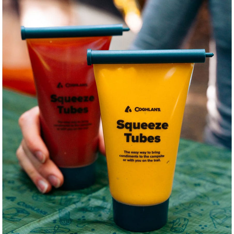 Load image into Gallery viewer, Two Coghlans Squeeze Tubes, one red and one yellow, on a green surface.

