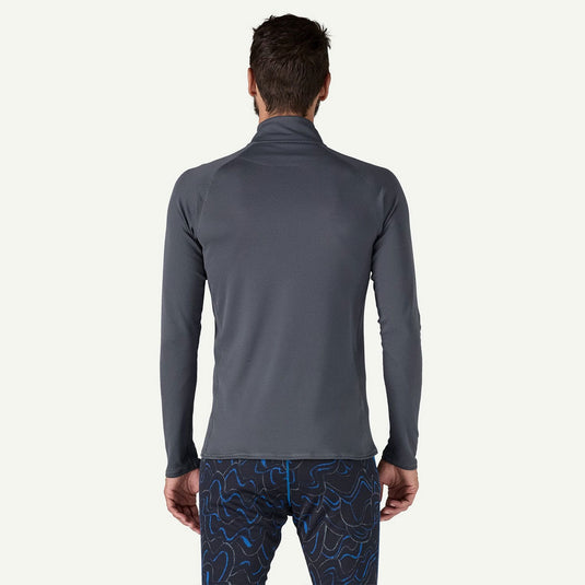 Person wearing a gray long-sleeve athletic shirt and patterned leggings on a white background