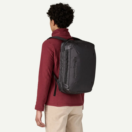 Person wearing a black Patagonia backpack on a white background