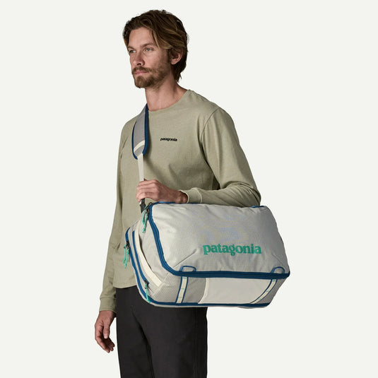 Man holding a white Patagonia duffel bag with blue trim against a white background