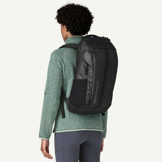 Person wearing a black backpack with Patagonia branding on a white background