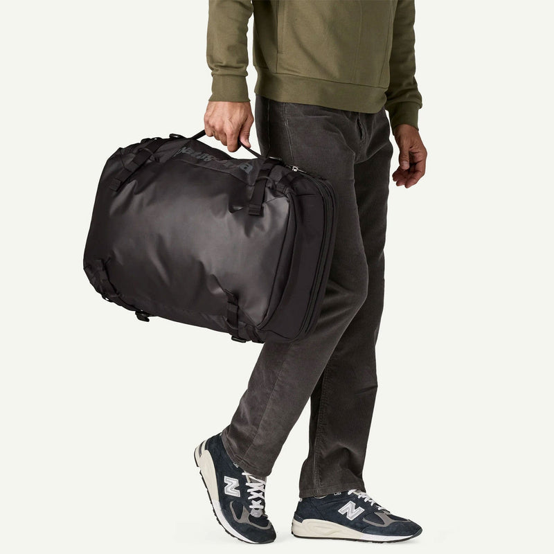 Load image into Gallery viewer, Person holding a black duffel bag on a plain background
