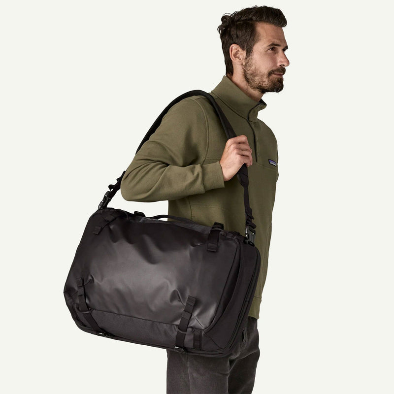 Load image into Gallery viewer, Man carrying a black duffel bag on a white background
