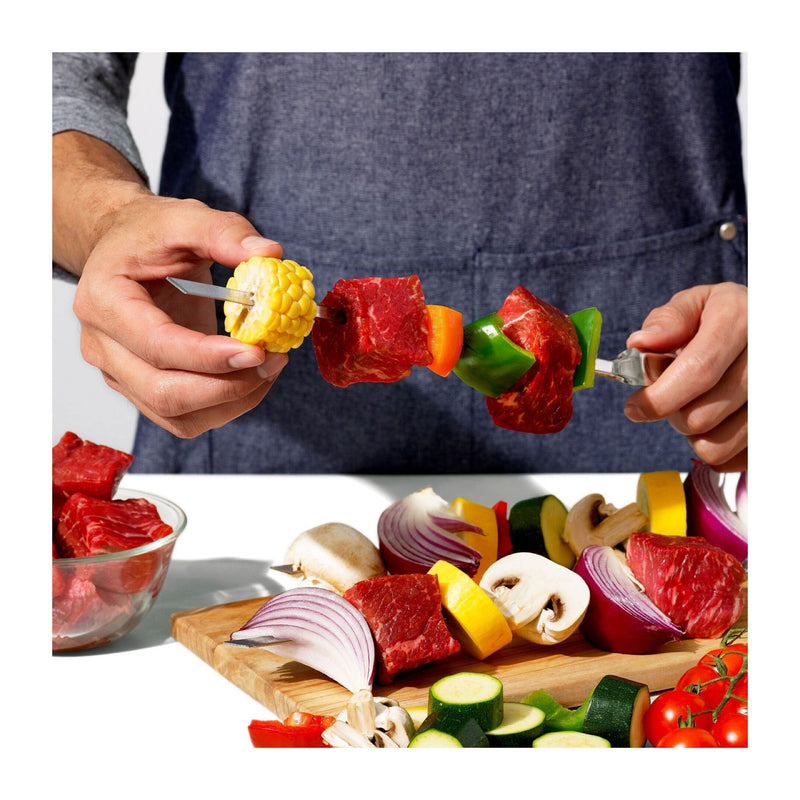 Load image into Gallery viewer, Person preparing a skewer with vegetables and meat on a cutting board.
