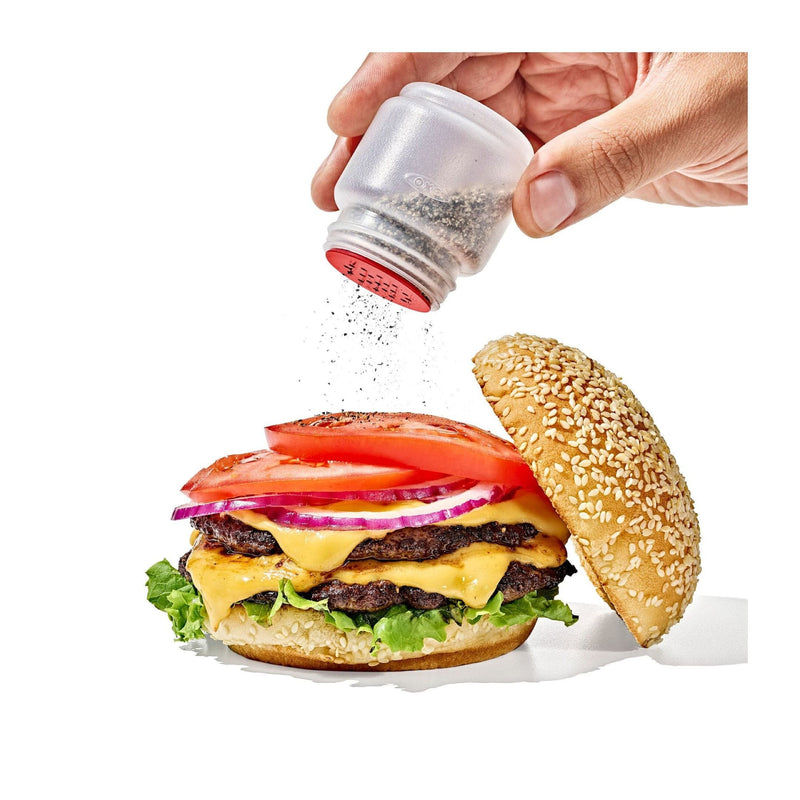 Load image into Gallery viewer, Hand sprinkling seasoning onto a burger with a salt shaker.
