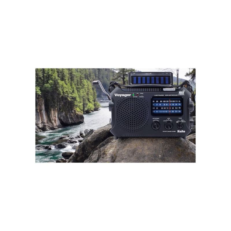 Load image into Gallery viewer, Black portable radio on a rock with a scenic background of trees and water.

