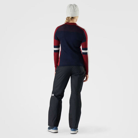Person wearing a navy and red sweater with dark pants on a white background