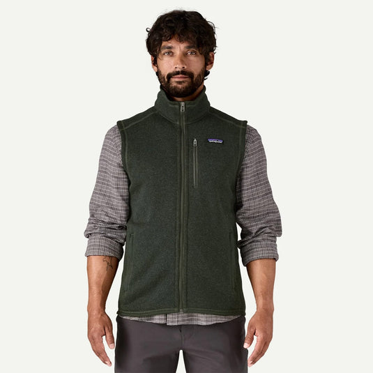 Man wearing a green fleece vest over a plaid shirt on a white background