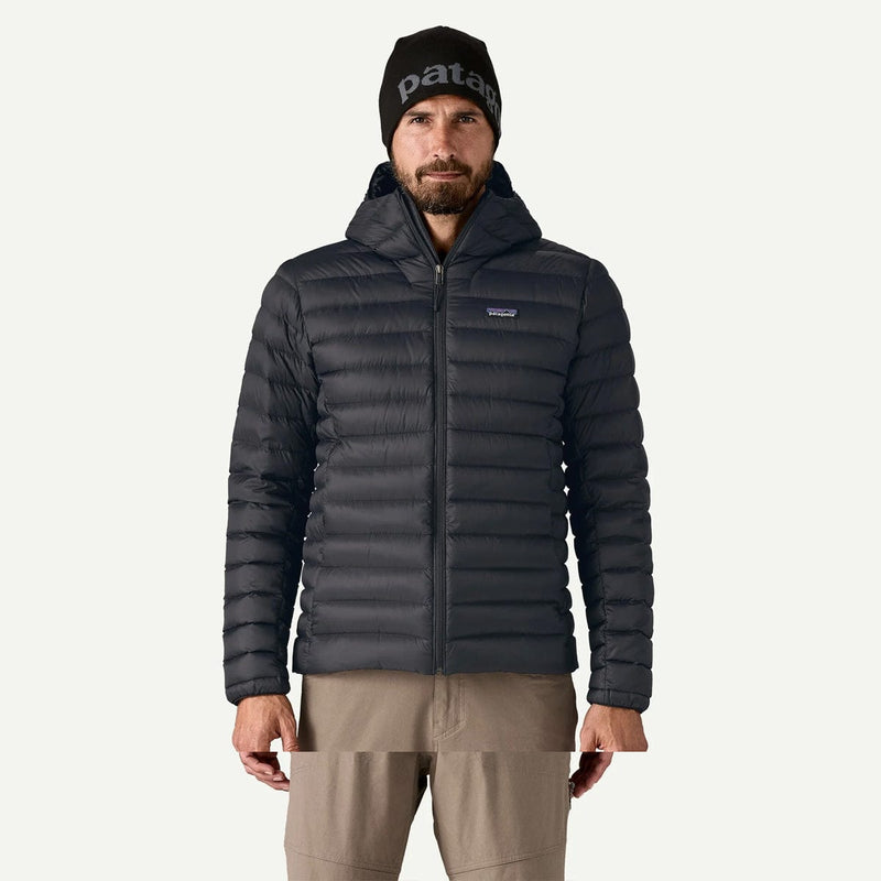 Load image into Gallery viewer, Man wearing a black puffer jacket and beanie with 'patagonia' branding on a white background
