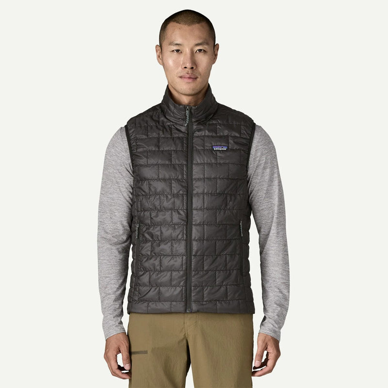 Load image into Gallery viewer, Man wearing a black quilted vest with a brand logo on a white background

