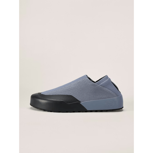 Blue slip-on shoe with black sole on a light beige background