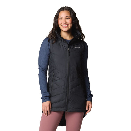 Woman wearing a black insulated vest over a blue long-sleeve shirt on a white background
