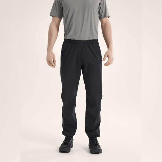 Person wearing black pants and a gray shirt on a beige background
