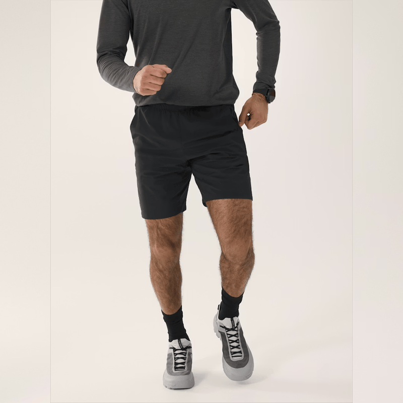 Load image into Gallery viewer, Person wearing black athletic shorts and gray sneakers on a white background
