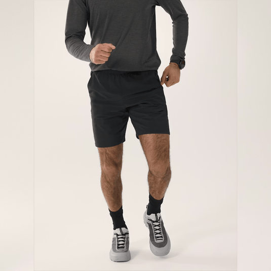 Person wearing black athletic shorts and gray sneakers on a white background