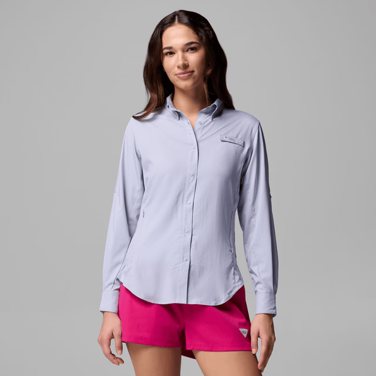 Woman wearing a light purple button-up shirt and pink shorts on a gray background