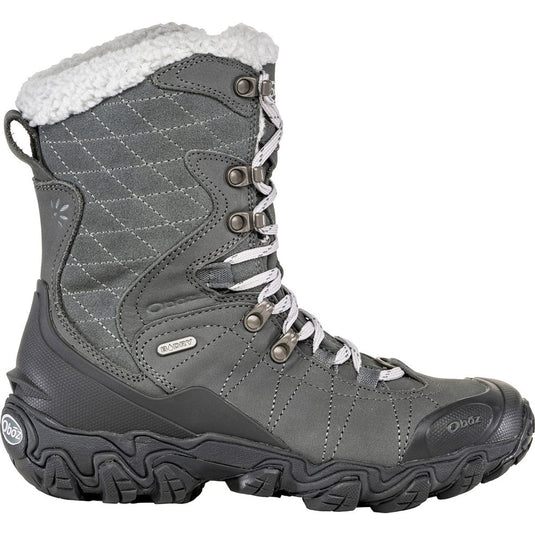 A woman's insulated hiking boot with a brown nubuck leather upper, waterproof membrane, and a black rubber outsole. It features pink lace hooks and a quilted design on the side.