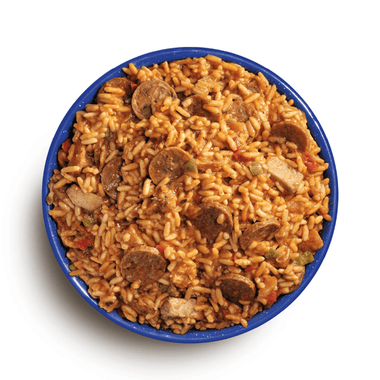 Bowl of jambalaya with sausage and vegetables on a white background
