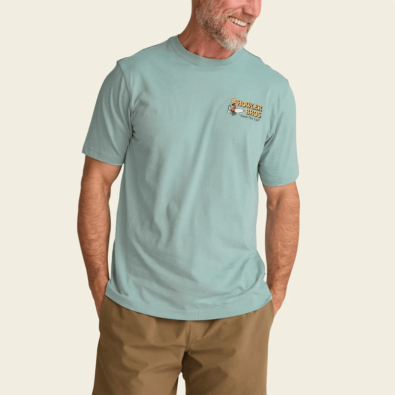 Load image into Gallery viewer, Man wearing a light blue t-shirt with a logo on a beige background
