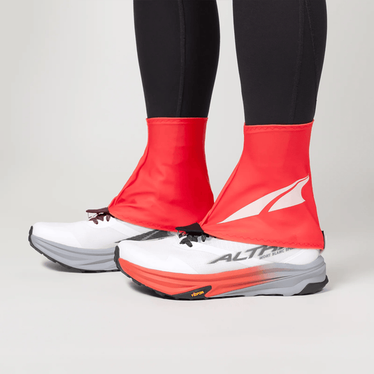 Red shoe covers over white running shoes with a visible brand logo on a neutral background