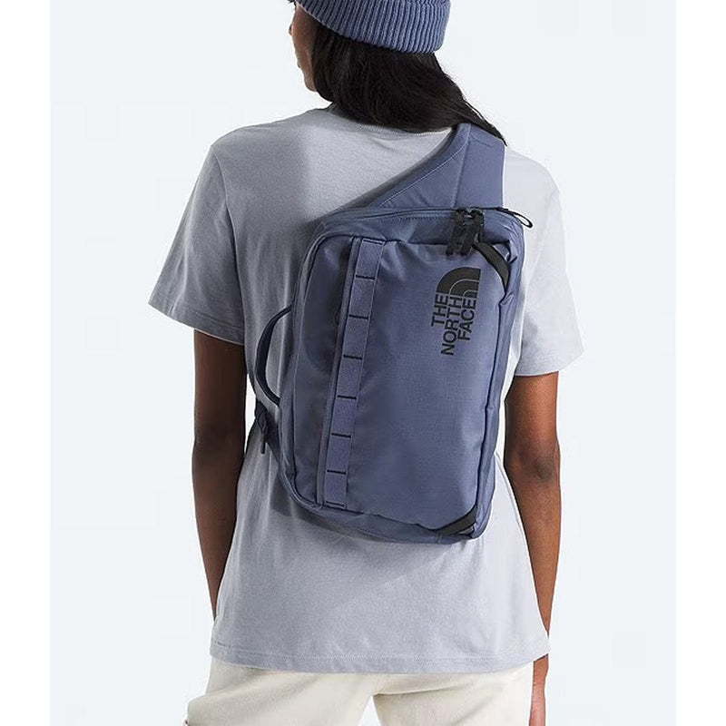 Load image into Gallery viewer, Person wearing a blue sling bag with The North Face logo on a white background
