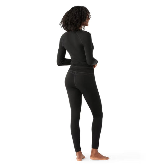 Person wearing black long-sleeve top and leggings on a white background