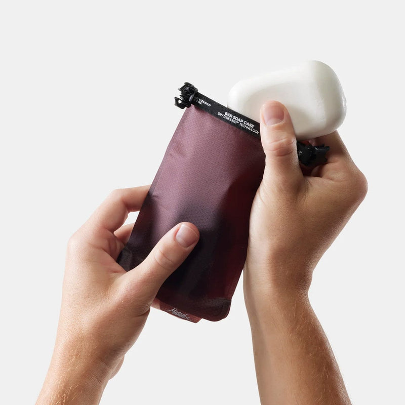 Load image into Gallery viewer, Person holding a purple compression bag with a white soap bar on a light gray background
