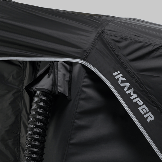 Close-up of a black rooftop tent with 'ikamper' branding on a gray background
