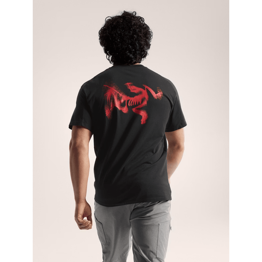 Person wearing a black t-shirt with a red graphic on the back against a neutral background