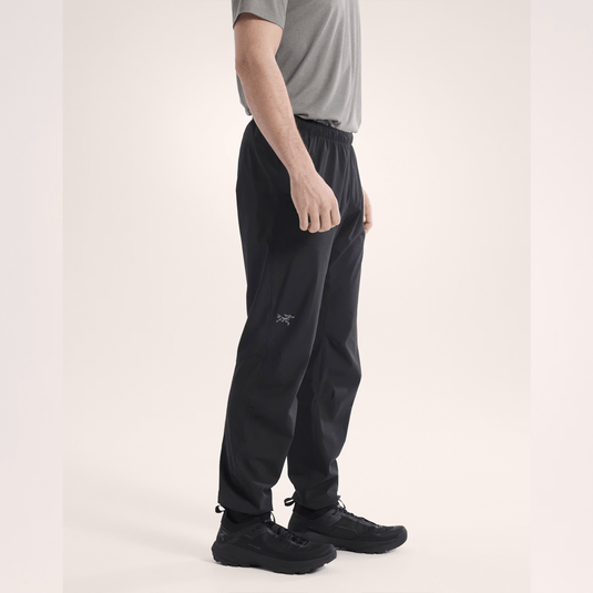 Person wearing black pants with a brand logo on a light background