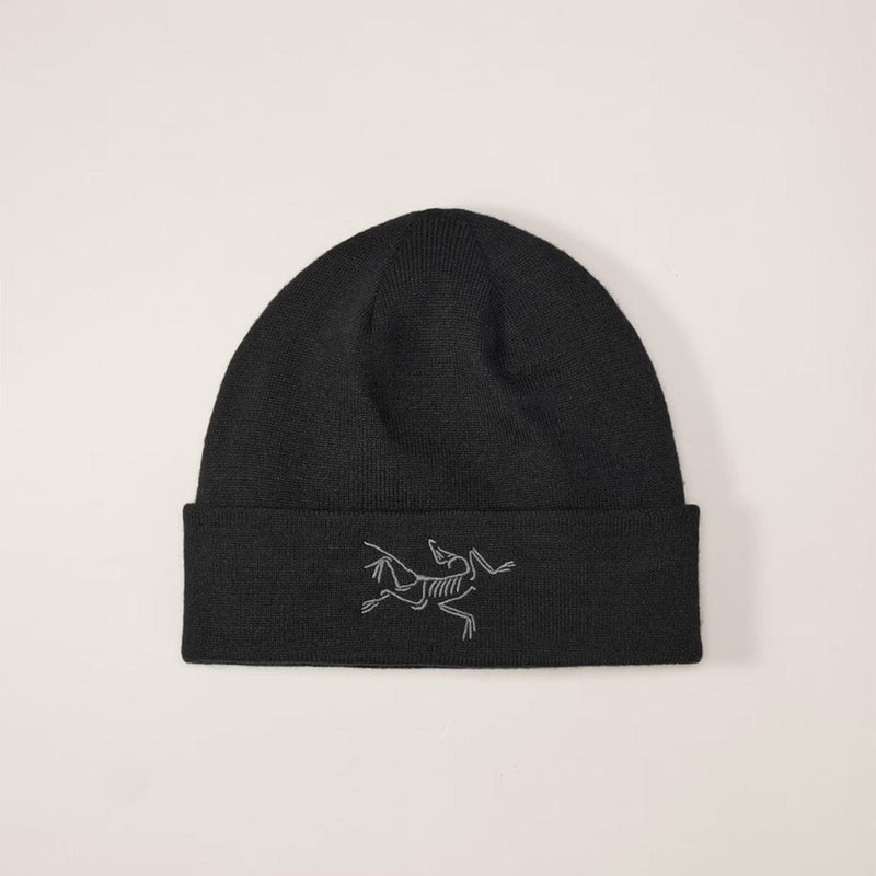 Load image into Gallery viewer, Black beanie with a white logo on a beige background
