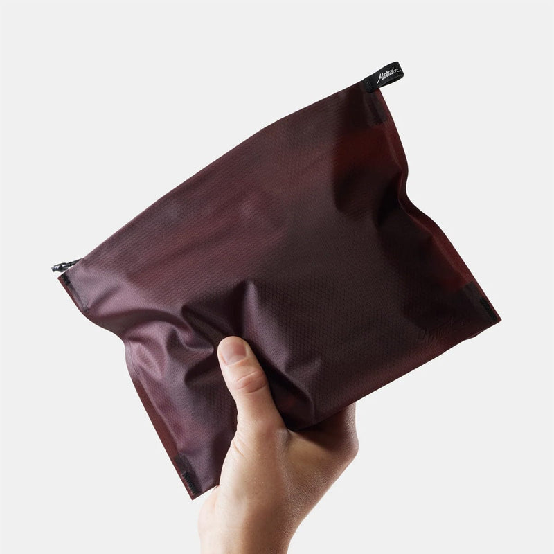 Load image into Gallery viewer, Hand holding a dark brown zippered pouch against a light background
