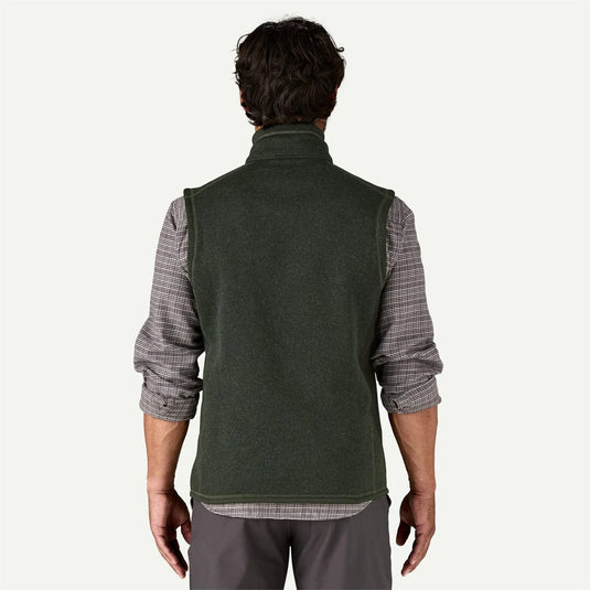 Man wearing a green vest over a plaid shirt on a white background