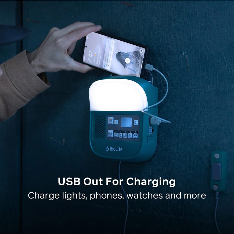 Load image into Gallery viewer, Person using a smartphone to charge a Biolite device on a dark surface
