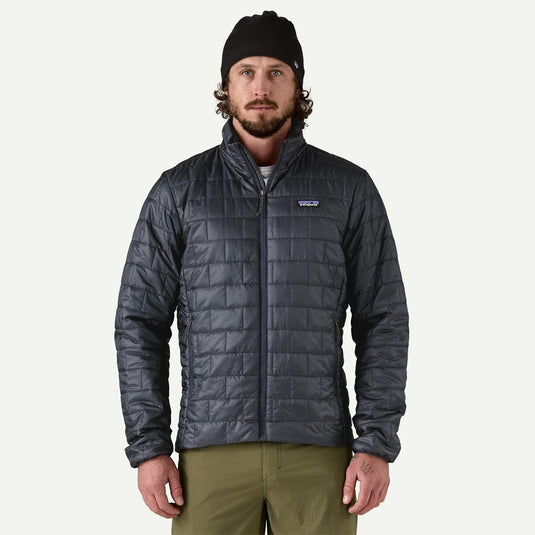 Man wearing a dark gray quilted jacket with a brand logo on a white background