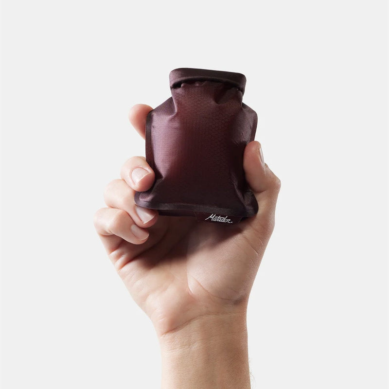 Load image into Gallery viewer, Hand holding a brown hot water bottle against a white background
