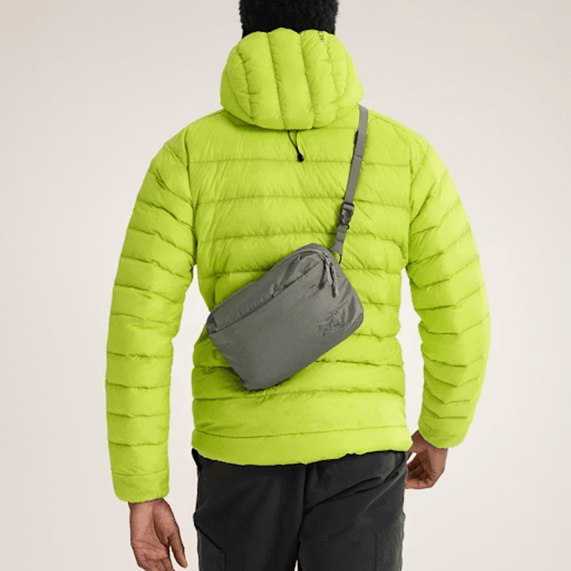 Load image into Gallery viewer, Person wearing a bright green puffer jacket with a gray crossbody bag on a beige background
