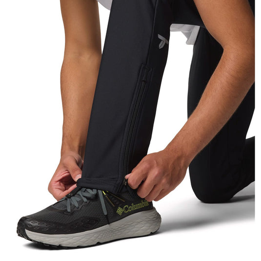 Person wearing black Columbia running shoes with pants pulled up to the knee on a white background